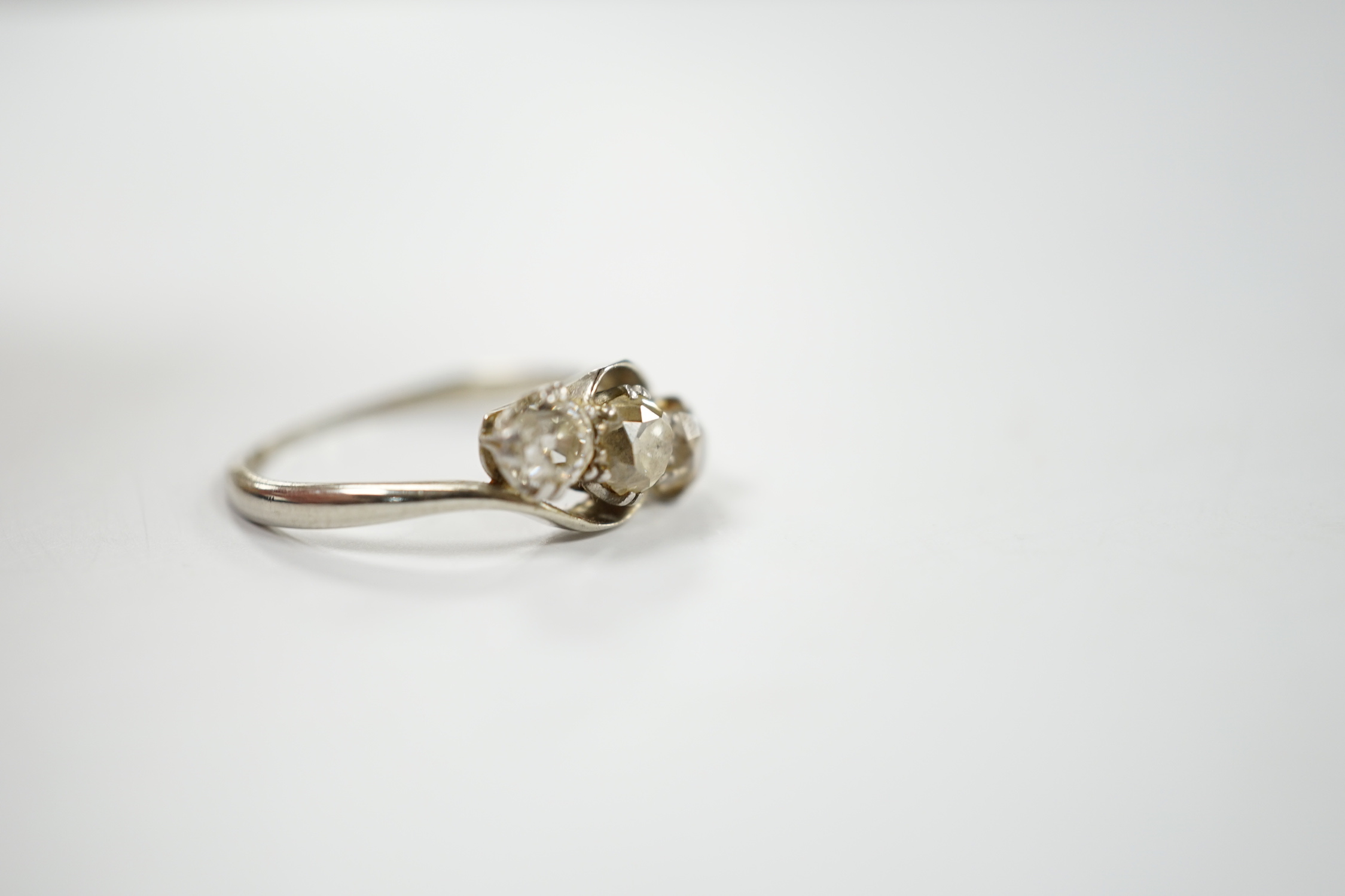 An 18ct, plat and three stone old mine cut diamond set crossover ring, size N, gross weight 2.3 grams.